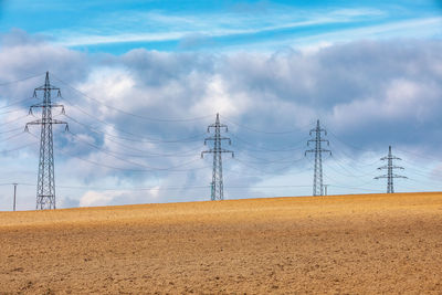 Electricity pylon on land against sky