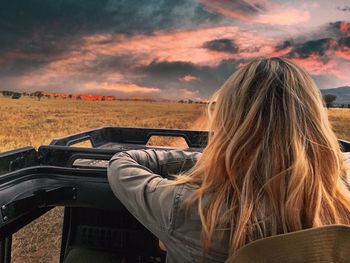Rear view of woman sitting in vehicle at serengeti national park against sky