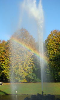 Scenic view of rainbow over trees against sky