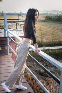 Side view of woman standing on railing