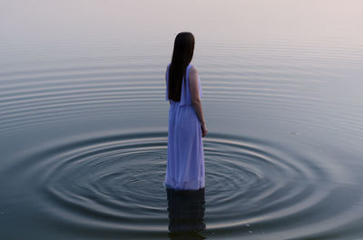 Rear view of woman standing in lake