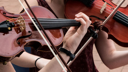 Midsection of woman playing violin on footpath in city
