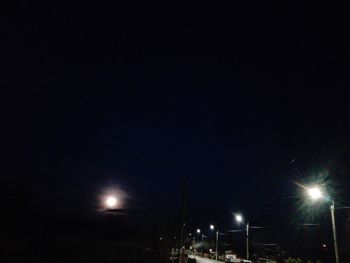 Low angle view of illuminated street lights against sky at night