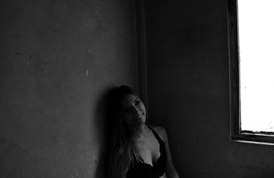 High angle view of smiling young woman looking away while sitting against wall at home