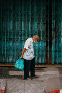 Side view of man standing against wall in city