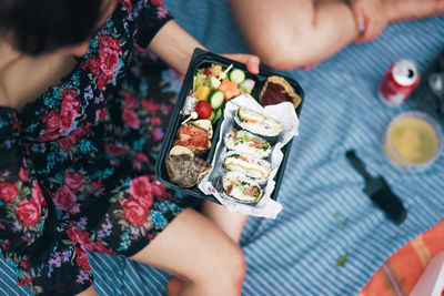 Cropped image of woman holding sushi in container
