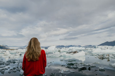 Woman in red jumper standing overlooking jökulsárlón glacier lagoon in iceland