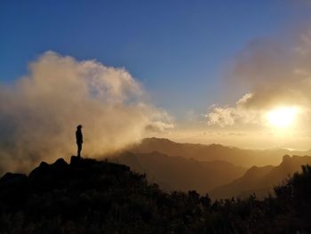 Silhouette man standing on mountain against sky during sunset