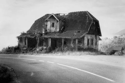 Abandoned building by road against sky