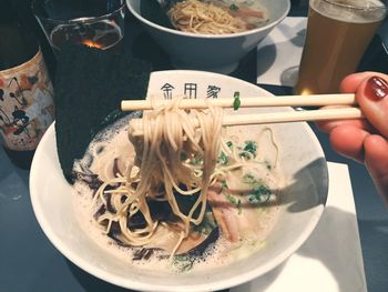 Cropped image of woman hand having ramen noodles with beer