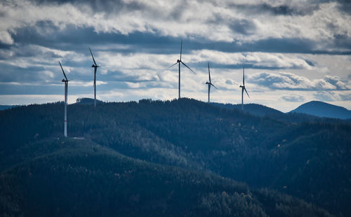 Wind turbines on land against sky