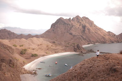 People on shore by mountains against sky