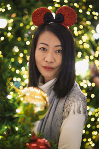 Portrait of young woman against christmas tree