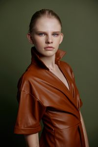 Portrait of young woman standing against black background