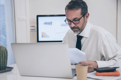 Business man working with laptop sitting at desk. male works at computer online with remote office