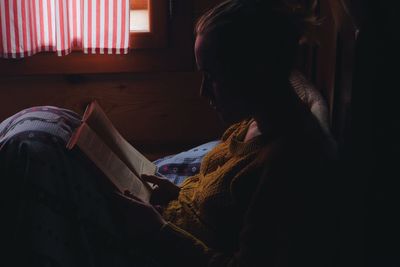 Young woman reading book on bed at home