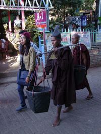 Full length of young woman with umbrella in city