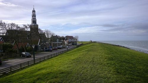View of buildings by sea against cloudy sky