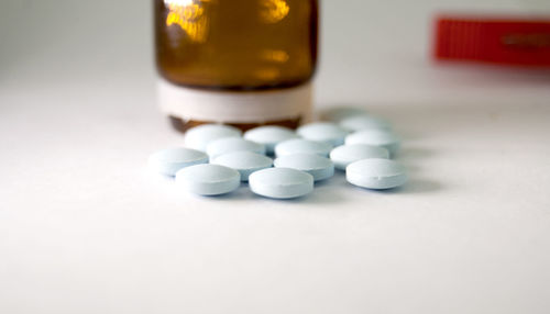 Close-up of medicine and bottle on white background