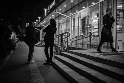 Rear view of people walking on illuminated city at night