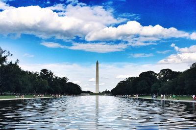 View of washington monument and trees against cloudy sky