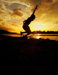 Silhouette man with arms raised against sky during sunset