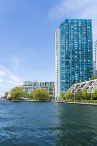 Buildings by river against sky