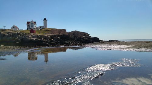 Lighthouse in sea against clear sky