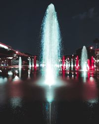 Illuminated fountain in city at night