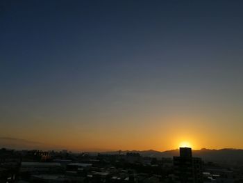 Silhouette buildings against clear sky at sunset