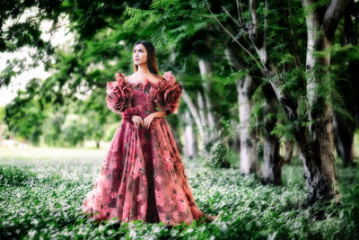 Woman standing by tree in forest