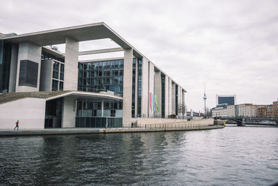 Buildings by river against sky in city