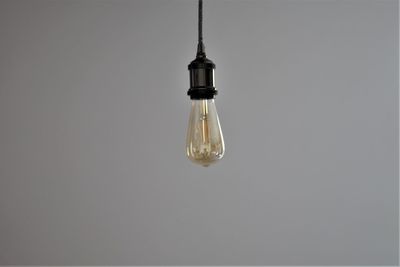 Light bulb hanging against gray background