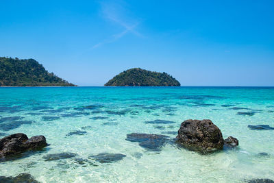 Scenic view of rocks in sea against blue sky