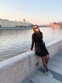 Full length portrait of young woman against sky