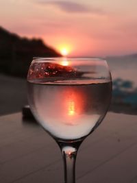 Close-up of beer glass against orange sky