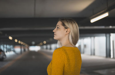 Young woman looking away while standing in underground parking lot