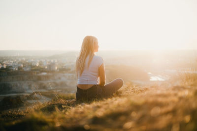 Woman sitting on land against clear sky