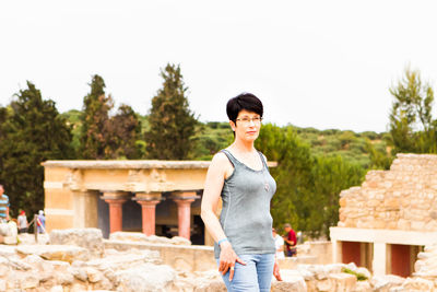 Portrait of smiling young woman standing against trees