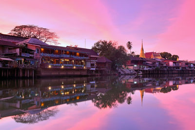 Reflection of buildings in lake against sky at sunset