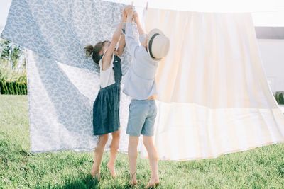 Siblings hanging the washing out to dry together in the backyard