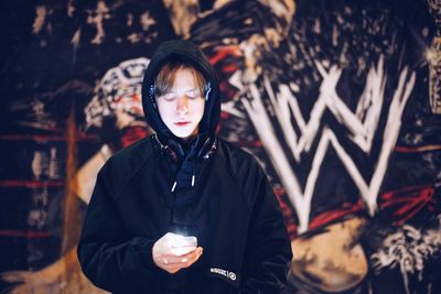 Portrait of young man standing against wall