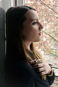 Side view of thoughtful beautiful woman leaning on wall