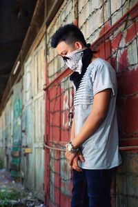 Portrait of a young man standing against brick wall