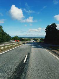 Road leading towards city against sky