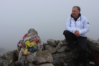 Smiling mature man sitting on rock