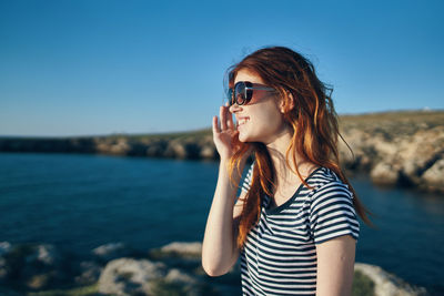 Beautiful young woman wearing sunglasses against sky