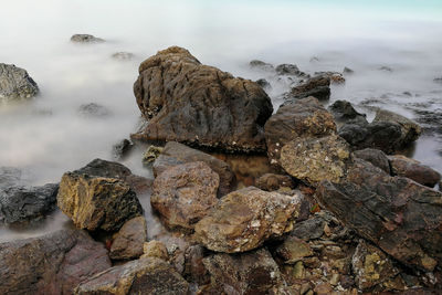 Rocks on sea shore against sky