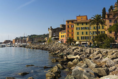 Buildings by sea against clear sky