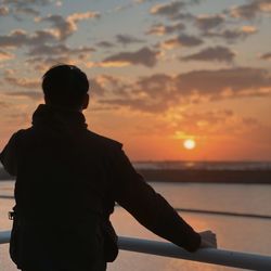 Rear view of silhouette man standing against sky during sunset